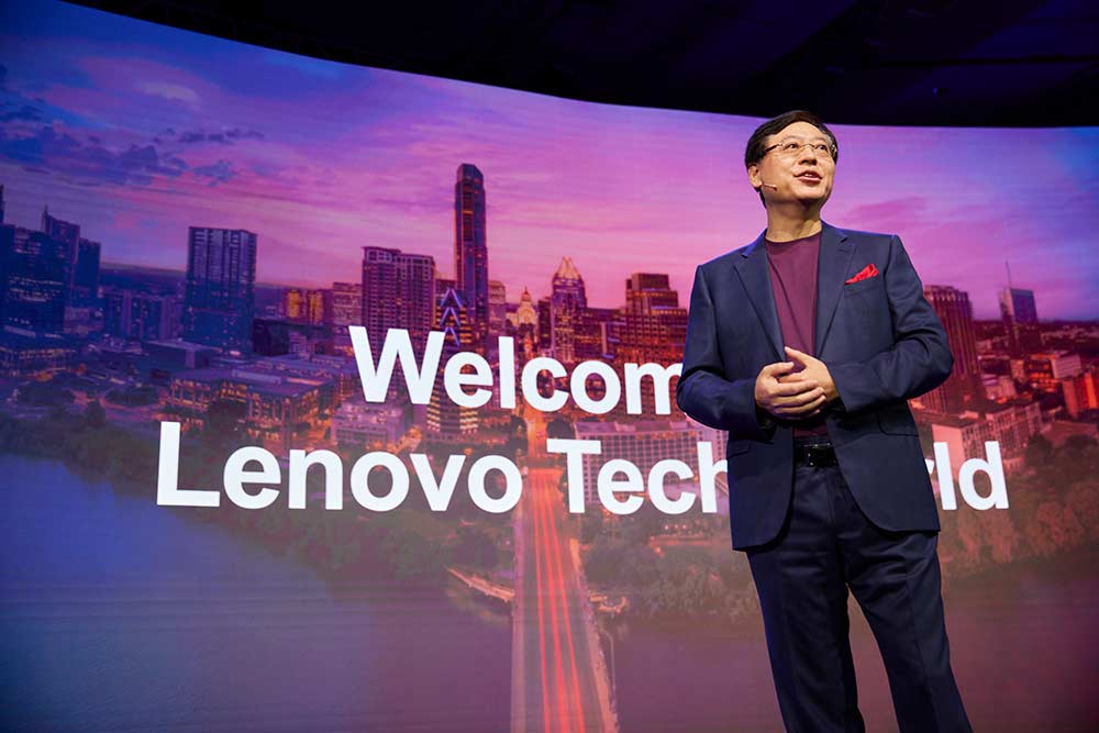 Medium shot of Lenovo's CEO, Yuanqing Yang, standing on the stage in front of a welcome screen