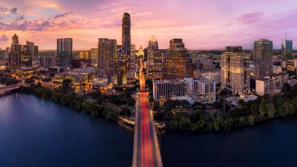 A bird's eye view of a bridge leading into Downtown Austin at dusk