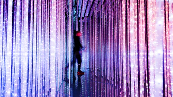 A person walking through a room with vertical streaming lights