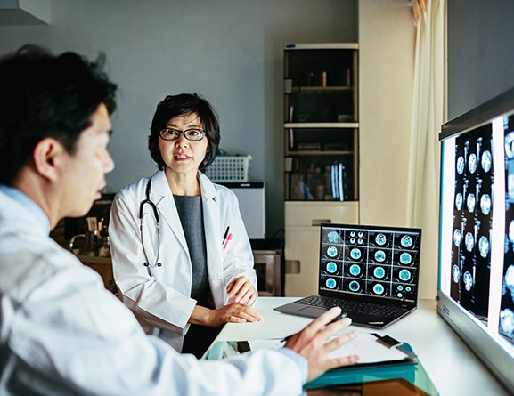 Hai bác sĩ đang xem hình ảnh quét y tế trên màn hình lớn, với máy tính xách tay Lenovo ThinkPad P16s Gen 2 (16 inch Intel), được mở trên bàn