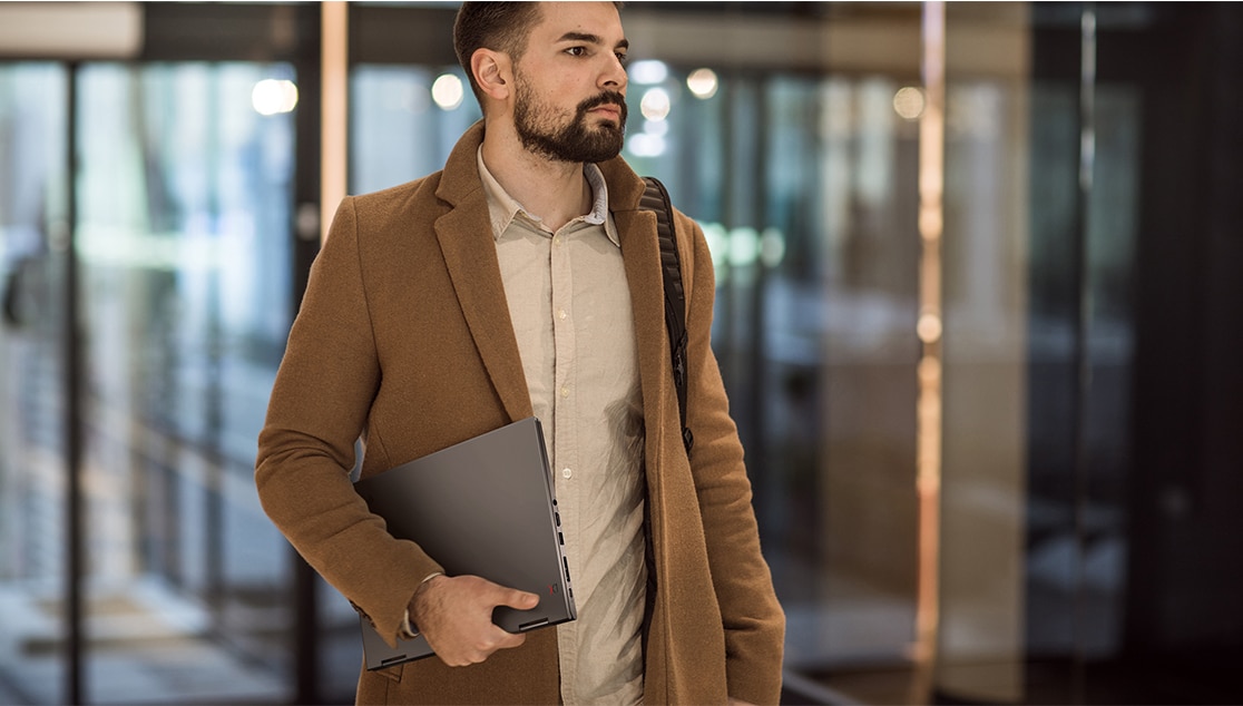 Hipster guy carrying a Lenovo ThinkPad X1 Yoga Gen 4  2-in-1 laptop under his arm.